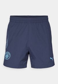 Un short bleu marine avec une ceinture élastique, un logo Puma bleu clair, et un blason de Manchester City bleu clair sur la jambe gauche.