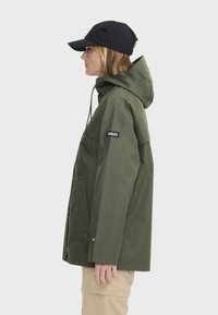 Veste imperméable verte avec capuche, dotée d'une fermeture éclair à l'avant, de deux poches latérales et d'un patch logo sur la manche gauche. Casquette noire.