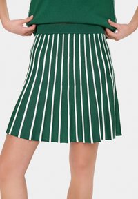 Jupe plissée verte avec des rayures verticales blanches, fabriquée en matériau tricoté texturé et dotée d'une taille élastique pour un ajustement confortable.