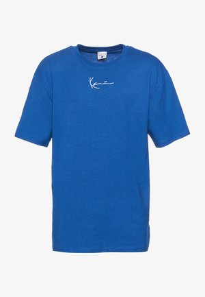 Kék pamut póló rövid ujjú, kerek nyakkivágással és fehér, kézzel írt logóval a mellkason. Puha tapintású és laza fazonú.