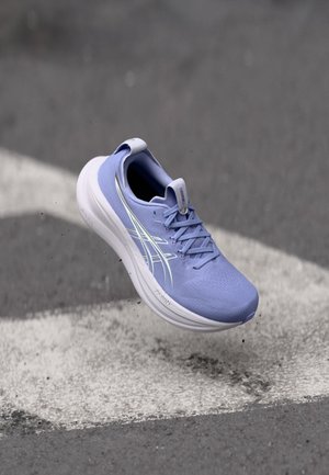 Lichtpaarse sportshoe met een bovenwerk van gestructureerde stof, witte zool en reflecterende accenten. Heeft veters en een trekhaak op de hiel.