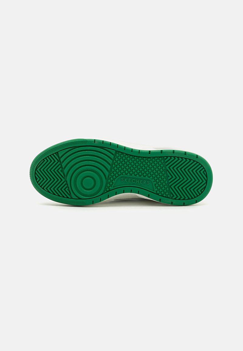 Semelle en caoutchouc vert avec motifs de grip texturés et marquage visible. Transition douce vers le bord supérieur blanc.