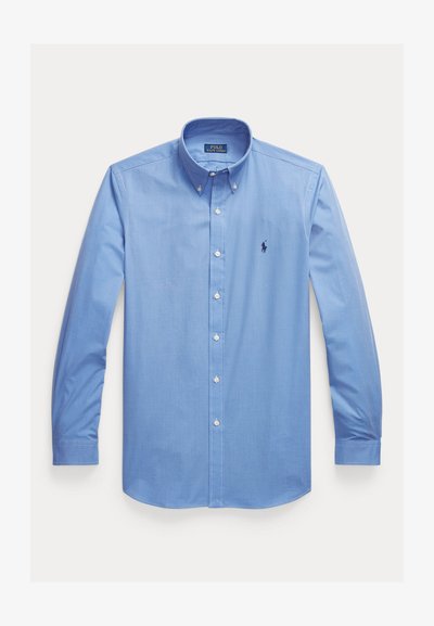 Cămașă cu mâneci lungi, de culoare albastru deschis, cu nasturi, guler cu nasturi și un mic logo brodat cu un cal albastru închis pe partea stângă a pieptului.