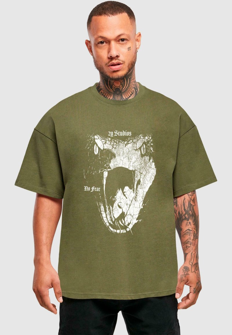 Olive zelené oversized tričko s bílou grafikou hada a textem "Žádný strach," s krátkými rukávy a kulatým výstřihem.