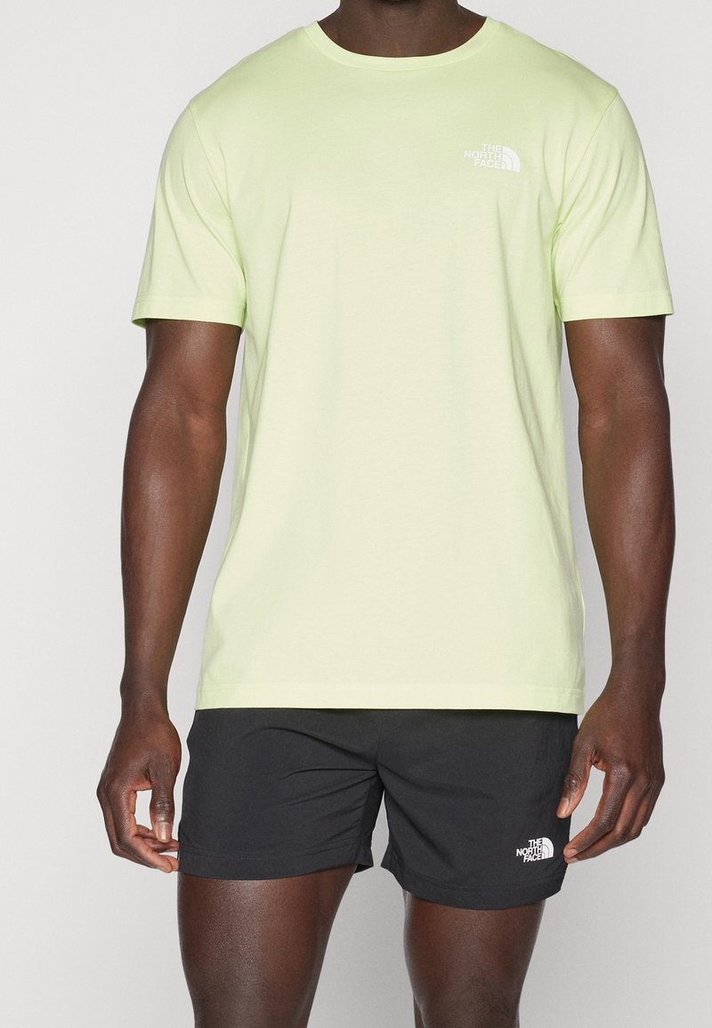 Světle zelené bavlněné tričko s krátkými rukávy a kulatým výstřihem, na levé straně hrudi s bílým logem. V kombinaci s černými šortkami.