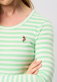 Groen en witte gestreepte lange mouwen shirt van ribstof, met een klein geborduurd detail op de borst.