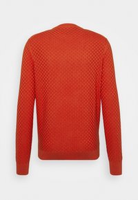 Maglione arancione a trama con un motivo geometrico, caratterizzato da un colletto rotondo e polsini a costine. Il tessuto appare morbido e caldo.