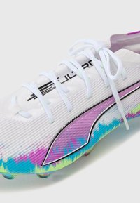 White football boot with textured upper, gradient pattern in pink, blue, and green. Black branding and white laces. Studded outsole.
