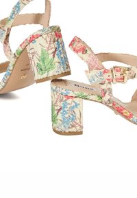 Floral print heeled sandals featuring a textured material, a chunky block heel, and an adjustable strap with a gold buckle accent.