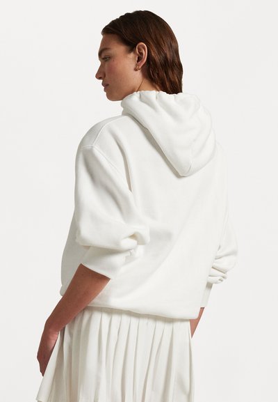 Sweat-shirt à capuche blanche avec une coupe décontractée, des épaules arrondies et des manches longues. Tissu doux avec des poignets côtelés et une capuche ajustable.