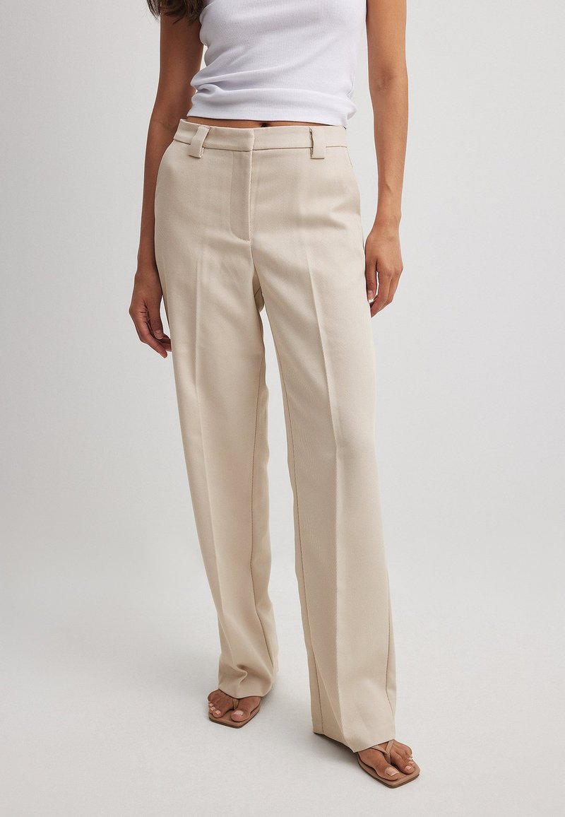 Beige weite Hosen mit glatter Textur, mit einem mittelhohen Bund, Seitentaschen und einem dezenten Nadelstreifenmuster.
