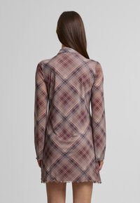 Rochie scurtă din țesătură transparentă, cu manșete lungi, guler, margine ondulată și o paletă de culori în nuanțe de mov, crem și bleumarin.