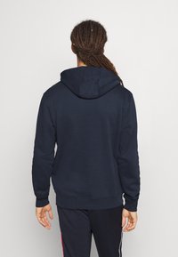 Felpa con cappuccio color blu navy realizzata in tessuto morbido. Presenta polsini e orlo a coste, con una vestibilità rilassata e senza decorazioni visibili.