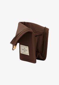 Portefeuille en tissu brun avec une finition texturée, comportant une fermeture à glissière et une étiquette mentionnant "THE FLAT LAY CO. LONDON." Design compact.