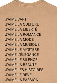 Beige T-shirt met zwarte tekst met verschillende zinnen die liefde voor kunst, cultuur en andere thema's uitdrukken, verticaal gestapeld op de achterkant.