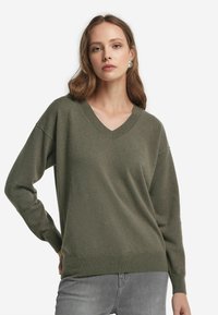 Olivengrüner Pullover mit V-Ausschnitt, gerippten Bündchen und Saum, aus weichem Stoff. Verfügt über einen lockeren Schnitt und überschnittene Schultern.