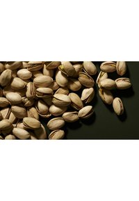 Des pistaches éparpillées sur une surface sombre, présentant des coques marron clair dont certaines sont ouvertes pour révéler les noix vertes à l'intérieur. Texture lisse.