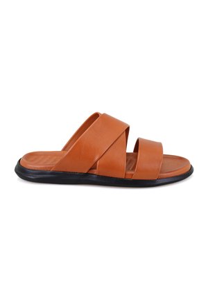 Tan leren slipper sandalen met twee overlappende banden, een platte zwarte rubberen zool en een gladde textuurafwerking.