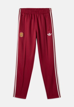 Pantaloni de trening bordo cu dungi albe laterale, talie elastică, emblemă națională a Spaniei pe coapsa stângă și logo-ul Adidas alb pe coapsa dreaptă.