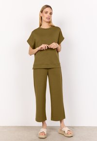 Completo da salotto verde oliva composto da una maglietta a maniche corte e pantaloni cropped a gamba larga in morbido tessuto testurizzato. Abbinato a sandali slip-on.