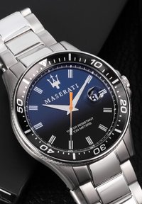 Orologio Maserati con quadrante blu, cinturino in acciaio inox argento, lancette arancioni e bianche, e display della data. Resistente all'acqua fino a 100 metri.