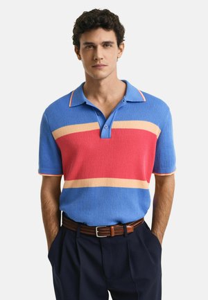Korte mouwen polo t-shirt in ribbelstructuur met blauw, rood en gele horizontale strepen, een stevige blauwe kraag en contrasterende biezen.