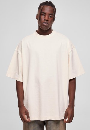 Kremfarget oversized t-skjorte laget av bomull, med rund hals og korte ermer. Glatt tekstur, avslappet passform og minimale designdetaljer.