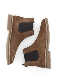 Bottines en daim marron avec des panneaux élastiques sur les côtés, des semelles en caoutchouc texturé et une languette de tirage. Design minimaliste avec un détail de couture beige.