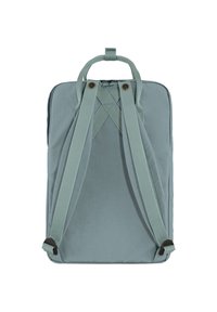 Nahrbtnik iz umirjene teal tkanine, ki ima pravokotno obliko, križni trak, nastavljive naramnice in dva rjava gumba kot okras.