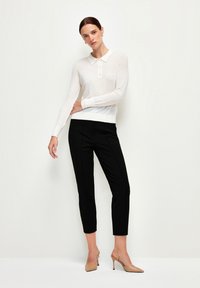 Witte polos met lange mouwen en knoopsluiting, gecombineerd met strakke zwarte broeken en naakte hoge hakken. Glad materiaal, elegante uitstraling.