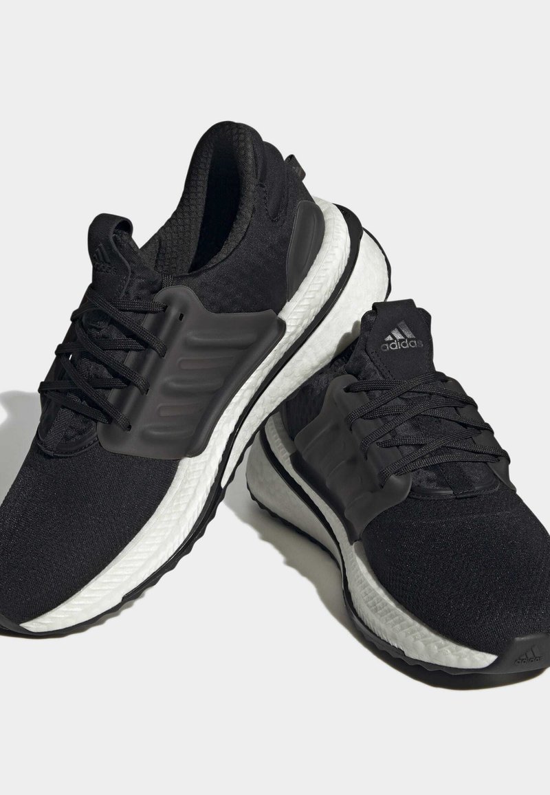 Schwarze Sportschuhe mit einem Obermaterial aus Mesh, strukturierten schwarzen Überzügen und einer weißen strukturierten Zwischensohle. Mit schwarzen Schnürsenkeln und Akzenten des Adidas-Logos.