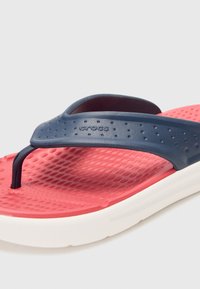 Infradito blu navy con suola rossa testurizzata, caratterizzati da un'ampia cinghia con perforazioni e un design minimalista. Costruzione leggera.