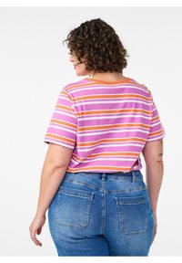 Lühikeste varrukatega t-särk roosade ja oranžide triipudega, ümmarguse kaelusega, kantud kõrge vöökohaga siniste teksapükstega.