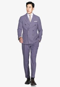 Traje de corte cruzado en una tela púrpura clara con una textura sutil. Presenta una camisa blanca, una corbata con patrón y zapatos de cordones marrones.