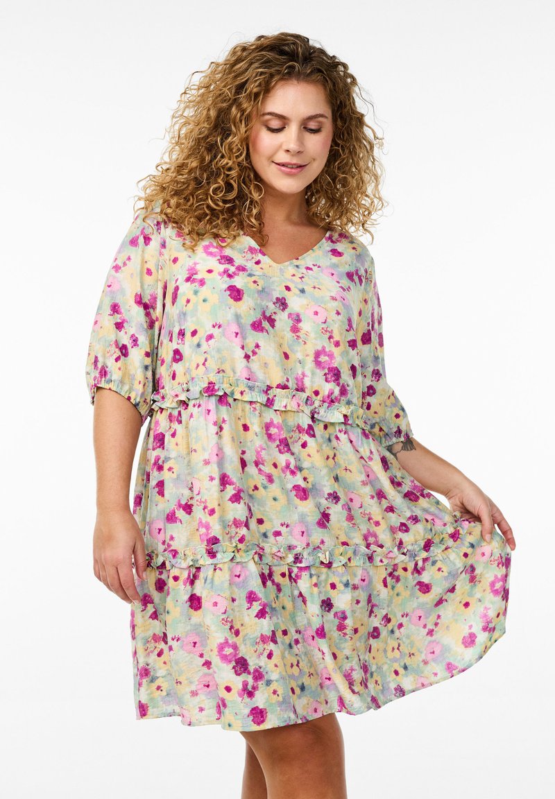 Robe florale dans des couleurs claires avec un décolleté en V, de courtes manches bouffantes, des volants superposés et des motifs de fleurs roses et violettes sur un fond pastel.