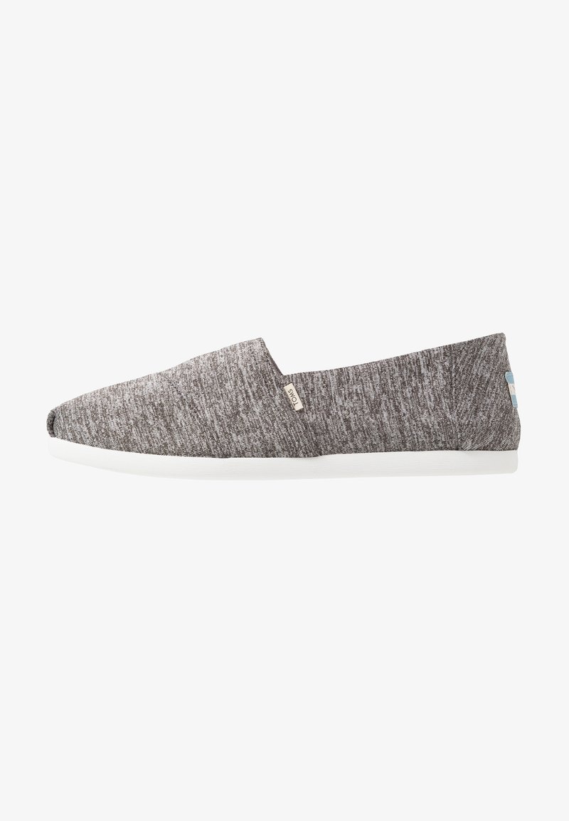 Chaussure décontractée grise à enfiler avec semelle blanche et petite étiquette de marque en tissu sur le côté, dessus en maille texturée, talon bas.