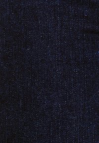Tummansininen farkkukangas, jossa on sileä tekstuuri. Ominaisuuksina klassinen twill-kudonta ja hienovaraiset sävyerot. Ei hardware- tai koristeita.