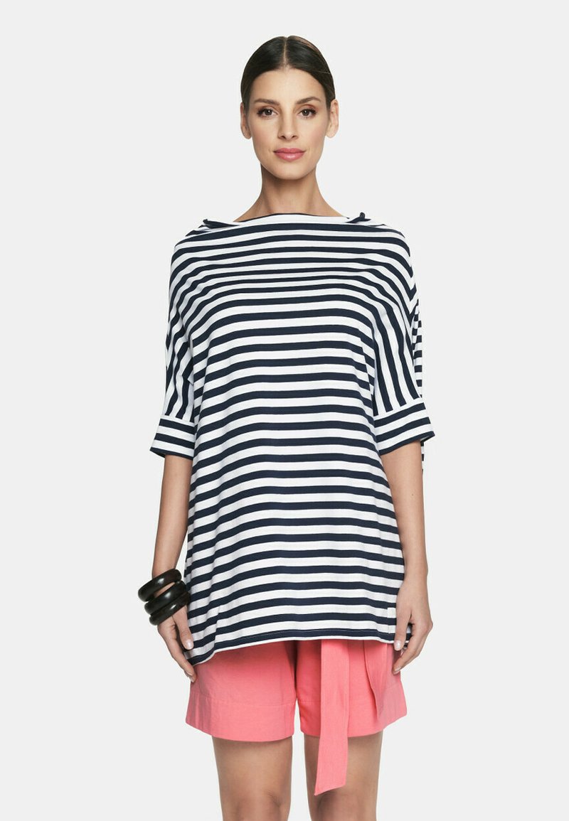 Pasiasty, oversize top w granatowo-białym kolorze z szerokim dekoltem i rękawami do łokci; w połączeniu z różowymi szortami z detalem wiązania.