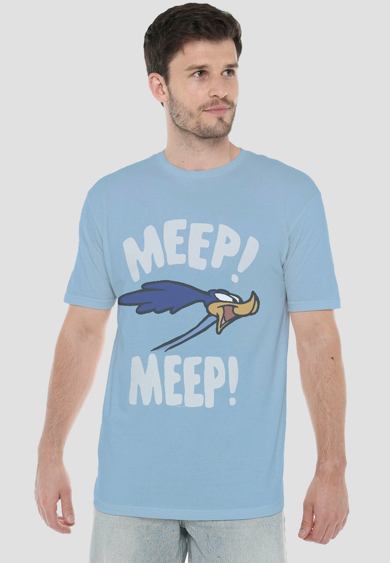 Man wearing light blue T-shirt with cartoon bird and text "MEEP! MEEP!" on front, standing against plain light background.