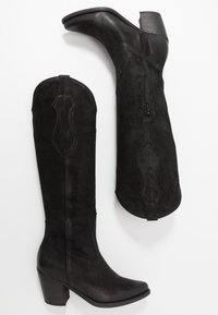 Botas negras altas de ante, con cremallera lateral, detalles de costura curvada y un tacón grueso. Textura suave con un acabado mate.