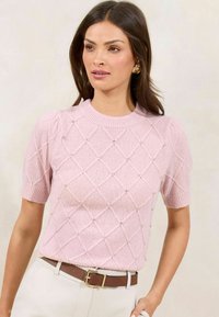 Short-sleeve pink sweater with diamond pattern, textured knit, and small crystal embellishments. Ribbed collar and cuffs, paired with a belt.