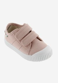 Baskets en toile rose avec deux brides Velcro, embout en caoutchouc blanc et semelle blanche texturée. Étiquette logo sur le côté.