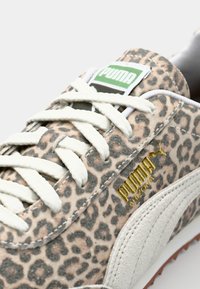 Tenisky PUMA s béžovým a hnědým semišovým svrškem s leopardím vzorem, kontrastující s bílými tkaničkami a zlatým logem na boku.