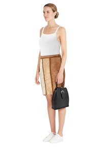 White ribbed tank top, brown suede skirt with vertical panels, and black handbag with a top handle. White sneakers complete the outfit.
