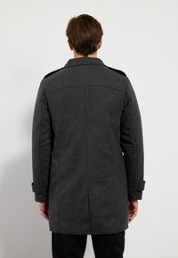 Abrigo de lana gris con un ajuste entallado, hombreras y puños abotonados. Presenta un corte recto y un diseño de espalda limpio.