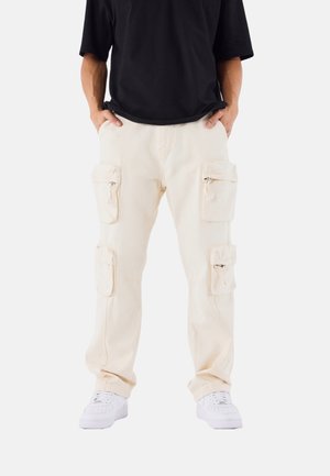 Pantaloni cargo color crema realizzati in tessuto resistente, dotati di numerose tasche frontali con cerniere, vestibilità comoda e polsini affusolati.