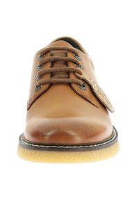 Chaussure en cuir marron avec un bout rond, un laçage, une surface texturée, une semelle en caoutchouc et une semelle extérieure jaune contrastante. Étiquette décorative sur le côté.