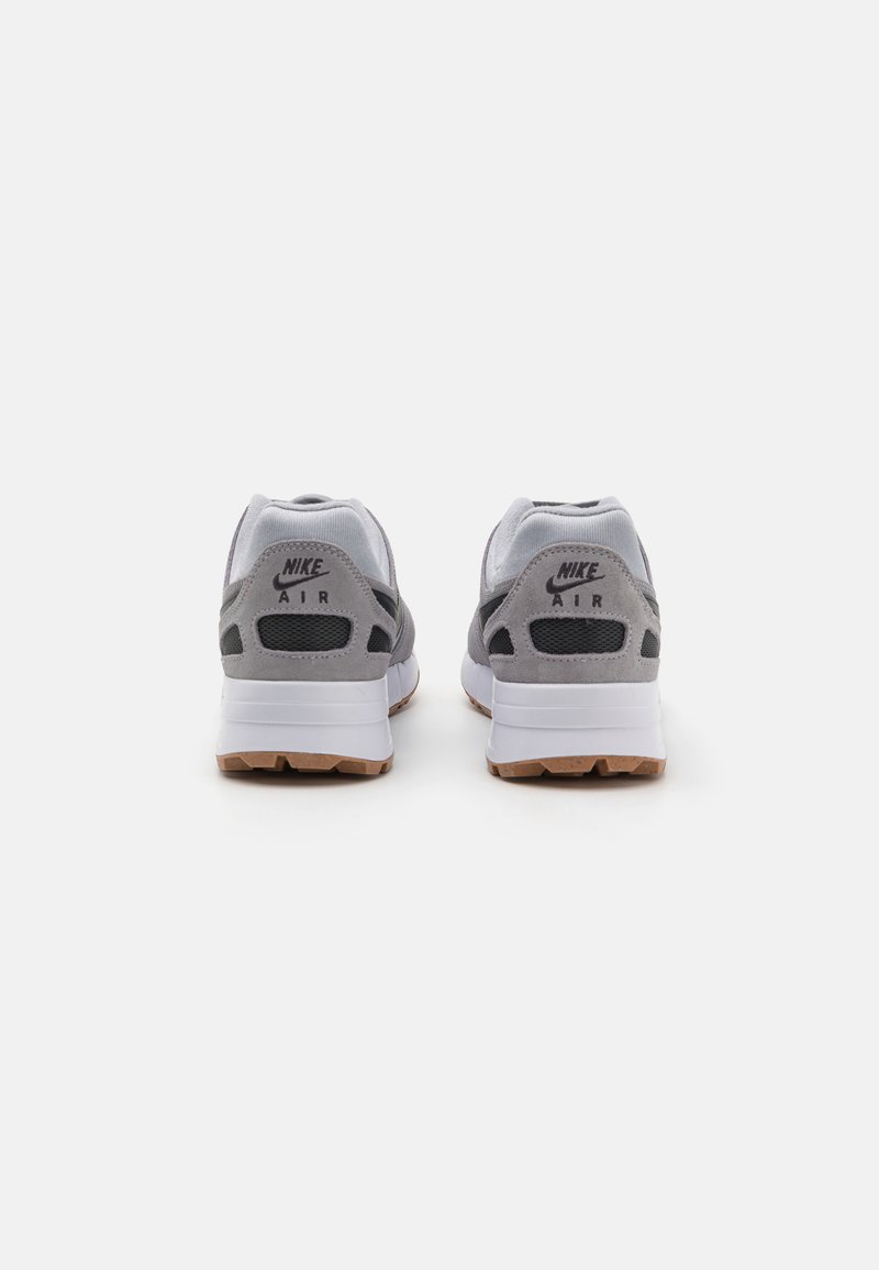 Baskets Nike Air avec une tige gris clair et blanche, des accents en daim, des panneaux en mesh et une semelle en caoutchouc avec un fond en gomme.