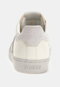 Sneaker bianca con dettagli beige, realizzata in materiali scamosciati e in pelle liscia, forma arrotondata, logo impresso sul tallone e suola in gomma texture.