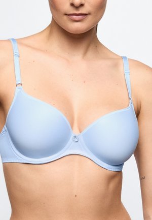 Woman wearing a light blue padded bra with adjustable straps, shown from shoulders to mid-torso against a plain background.